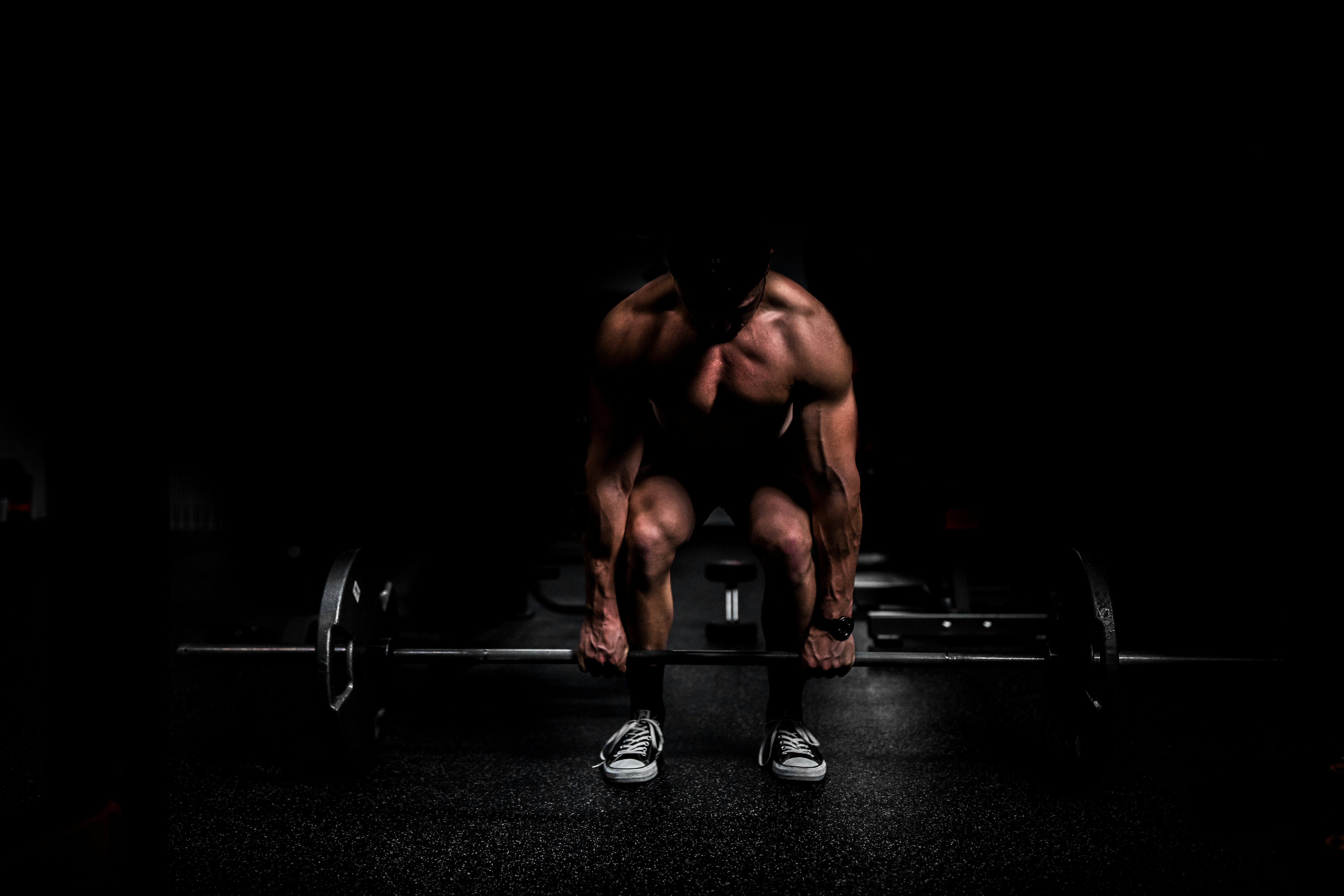 Muscular lifter gripping a barbell before a deadlift — periodization training